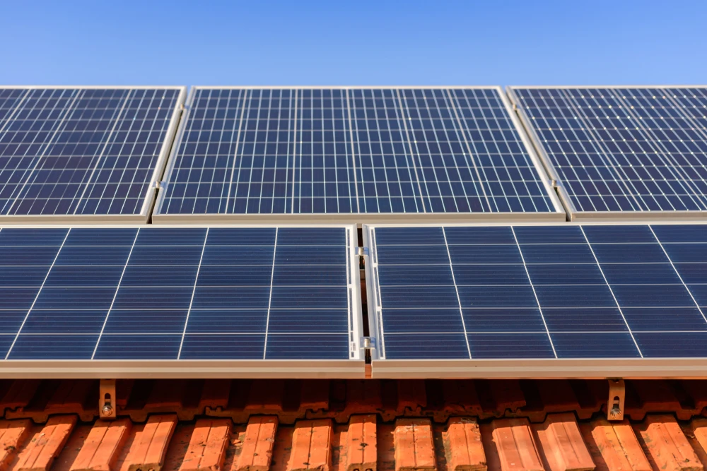 Scène extérieure montrant une installation de panneaux solaires photovoltaïques montés sur une toiture en tuiles terre cuite