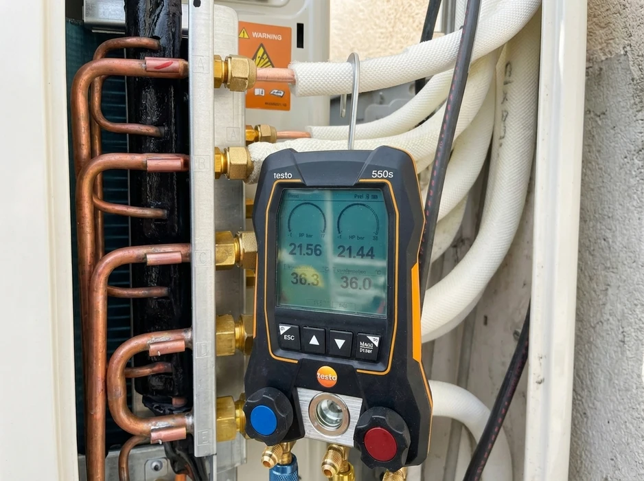 Technicien en climatisation effectuant des mesures sur une installation frigorifique extérieure