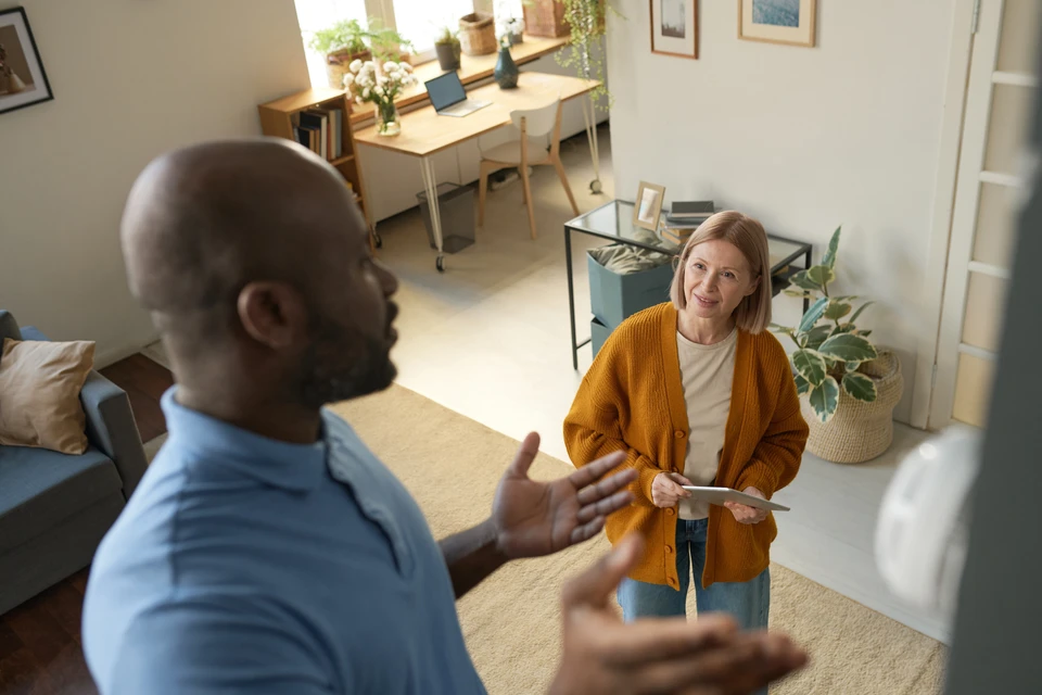 Gros plan sur un toit de maison avec des panneaux solaires au dessus, sur un ciel bleu avec des nuages et des rayons du soleil