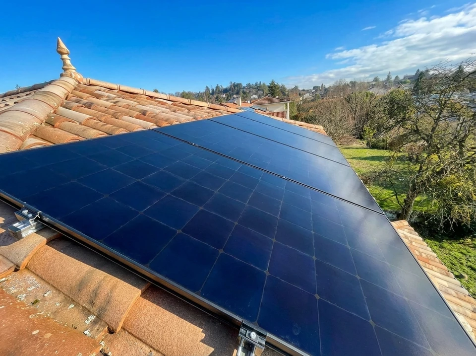 Deux techniciens installent des panneaux solaires photovoltaïques sur une toiture résidentielle en tuiles