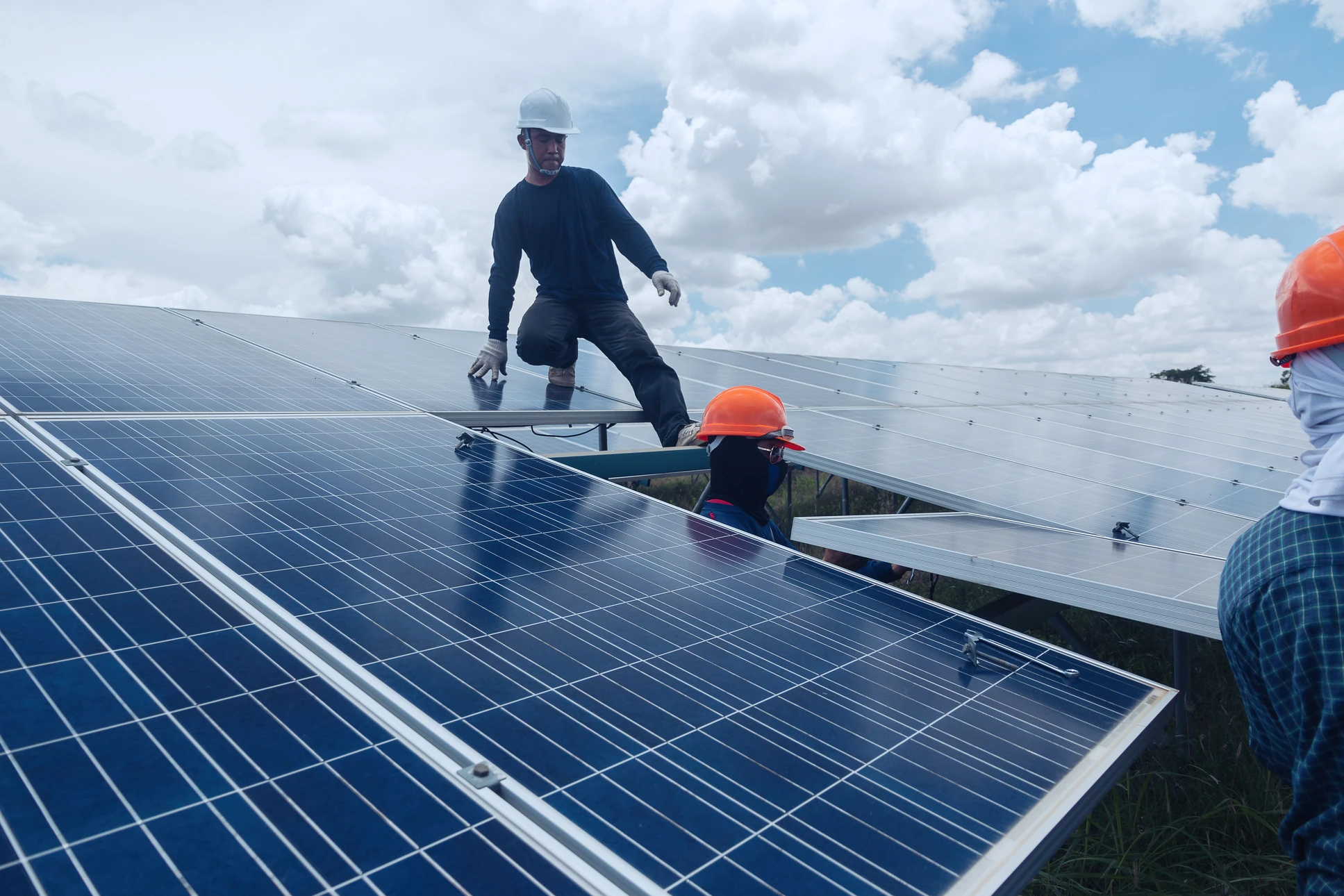 Deux professionnels sur un toit analysent des données sur tablette numérique près d'une installation de panneaux solaires photovoltaïques