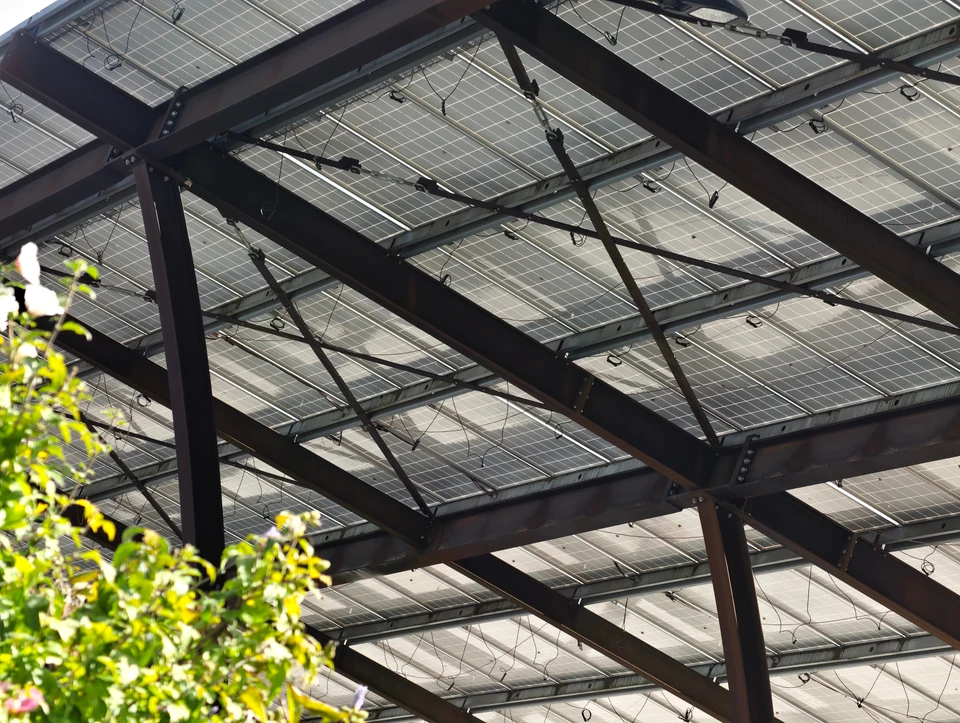 Scène extérieure de travaux de toiture avec deux ouvriers installant des panneaux solaires sur un toit résidentiel sous un ciel bleu dégagé